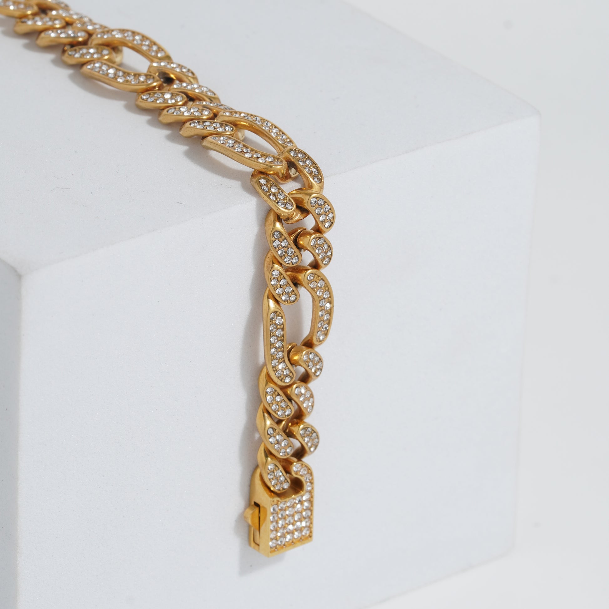 Gold chain bracelet with diamond-like stones on a white background