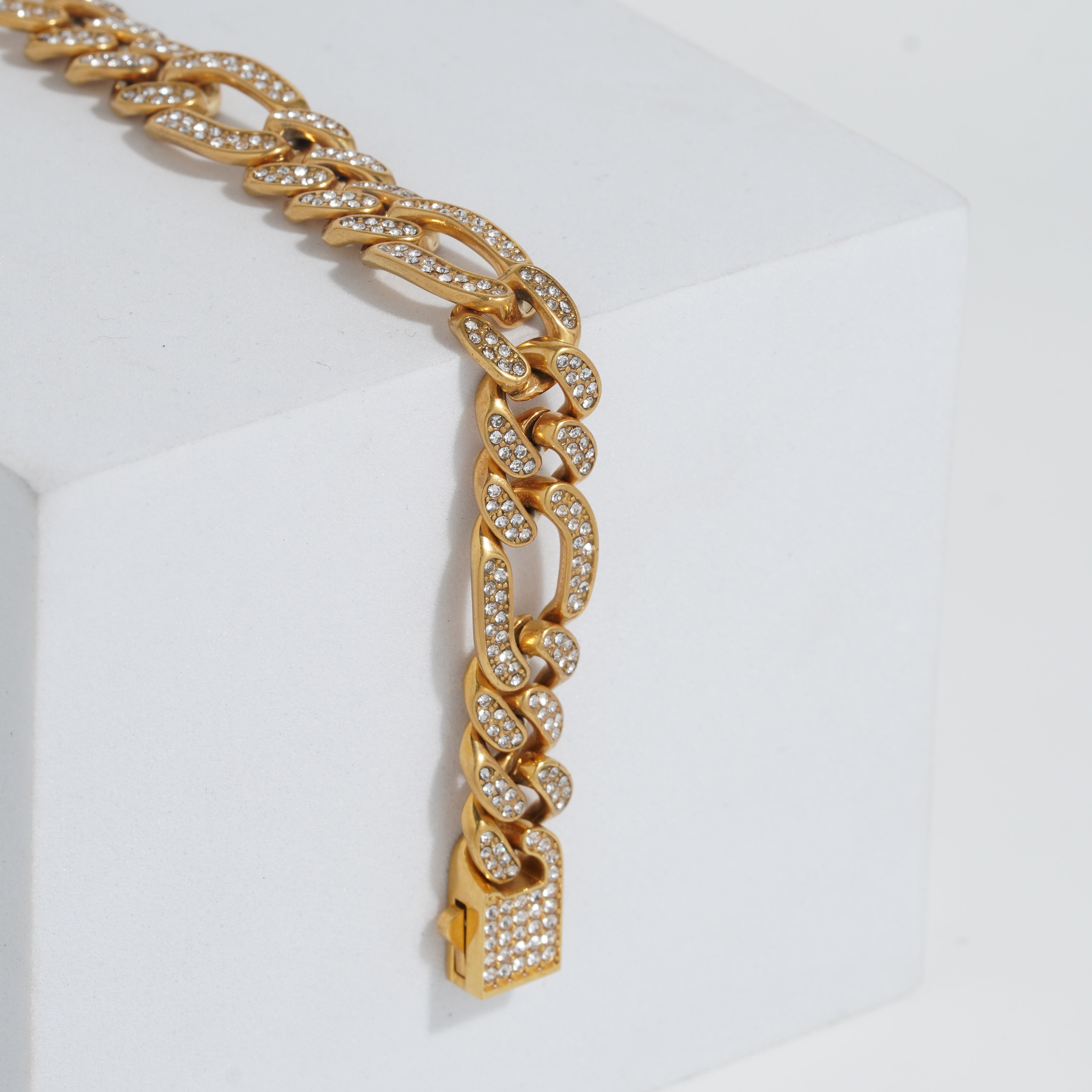 Gold chain bracelet with diamond-like stones on a white background