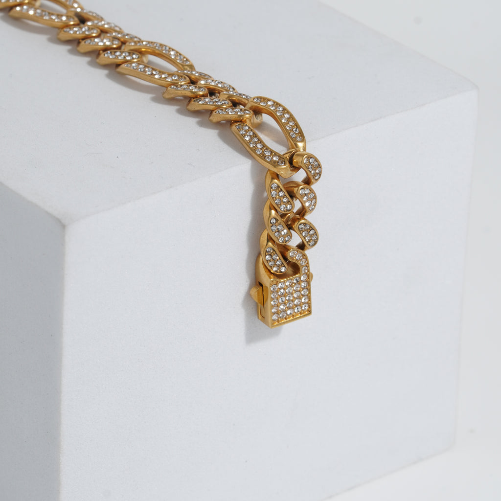 Gold chain bracelet with diamond-like stones on a white background