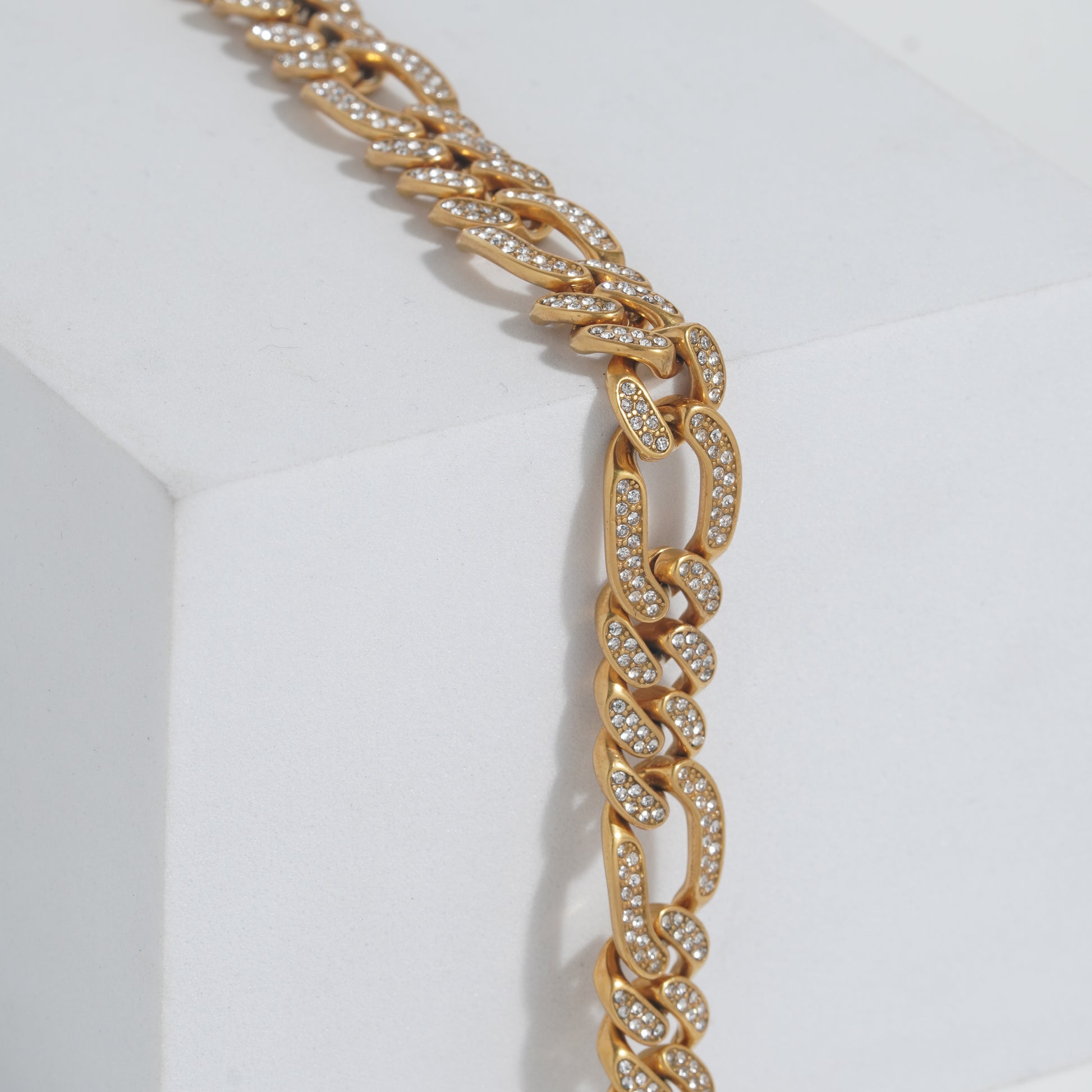 Gold chain necklace with embedded stones on a white background